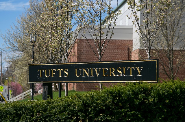 图中是塔夫斯大学的一个标志，它的后面是盛开的树木